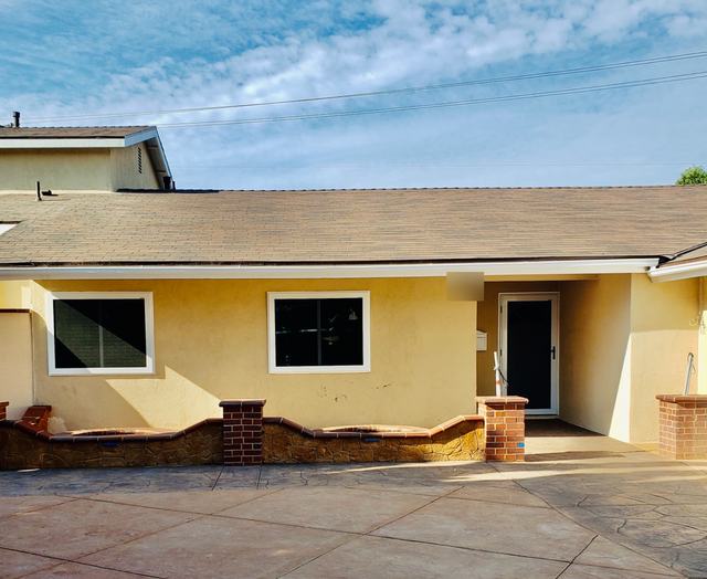 Yellow stucco ranch home with a hinged security screen door and security screens on two front windows