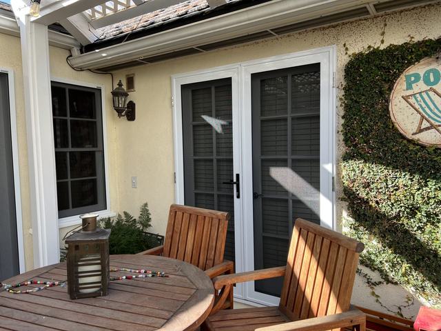 White French-door security screens opening onto a patio with wooden chairs
