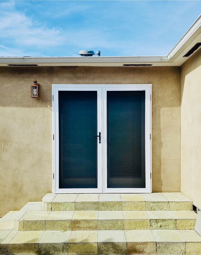 White double security screen doors on a tan stucco wall above stone steps