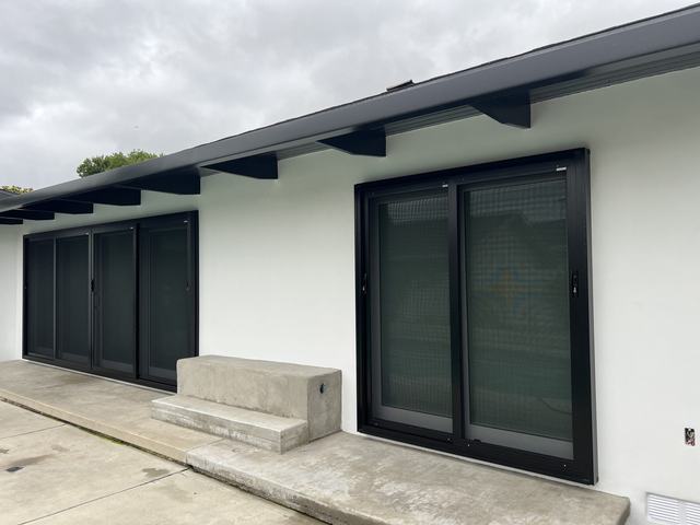 Two black sliding security screen doors, a double and a four-panel, along the back of a white home