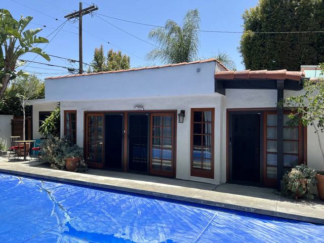 Pool house with wood-framed doors fitted with black sliding security screens, beside a covered pool