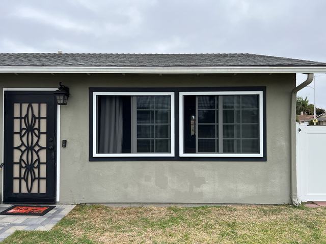 Two white-framed fire-escape security screens on the front windows of a green stucco home