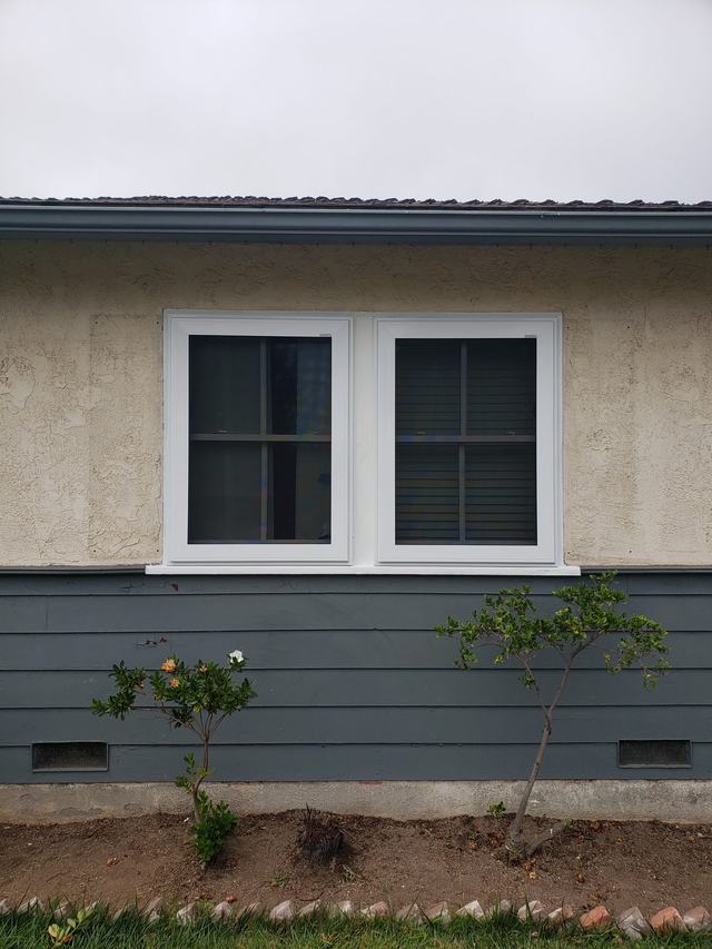 Two white-framed fire-escape security screens on side-by-side windows above gray siding