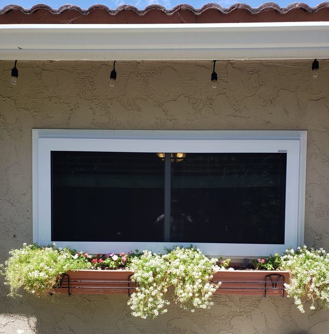 White-framed fire-escape security screen on a wide sliding window above a flower box