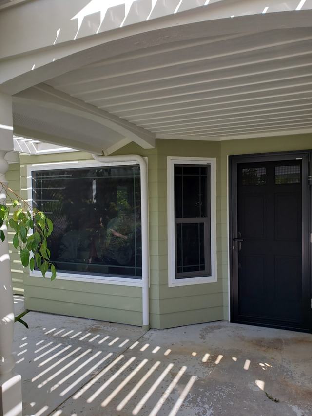 Fixed security screens on a bay window and a tall window beside a black hinged security screen door
